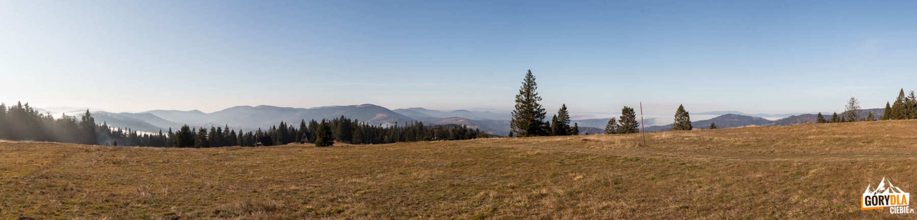 Panorama z górnej części Hali Krawcula: od lewej Oszust (1155 m), Mała Fatra, Świtkowa (1082 m), Rycerzowa Wielka (1226 m) i Rycerzowa Mała (1207 m), Wielka Racza (1236 m), Muńcuł (1165 m), Praszywka Wielka (1043 m), Magura (1073 m), Oźna (952 m), Rochowiec (954 m) i Sucha Góra (1040 m), Sucha Góra (1040), Redykalny Wierch (1144 m), na horyzoncie grań Beskidu Śląskiego od Baraniej Góry (1220 m) po Skrzyczne (1257 m), a na hali szałas, Bacówka PTTK i krzyż